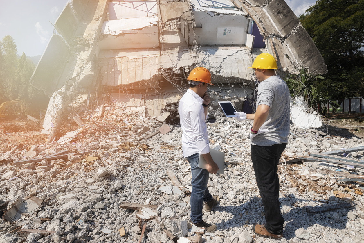 Two workers at the disaster site assessing the damage. 