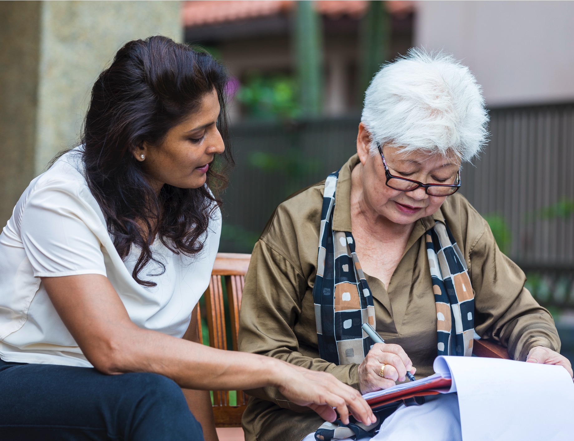 Senior woman signing documents in front of the representative.