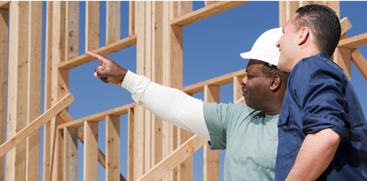 Two construction workers reviewing plans at a construction site. 